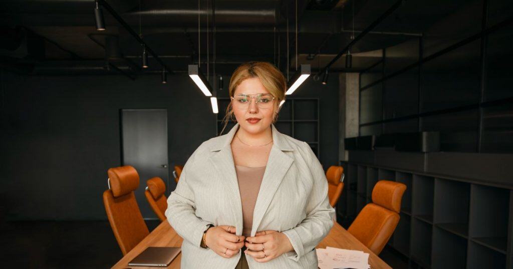 a confident woman standing in her office at the head of the meeting table showing her authority over her narcissist employees.
