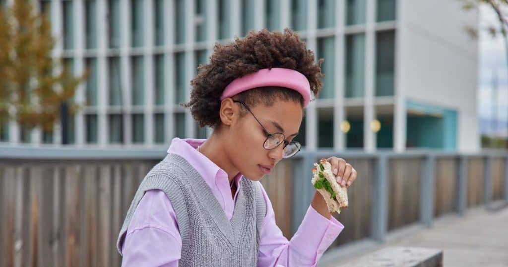 a woman sitting outside eating her lunch while finishing up her work determine to improve herself daily to succeed despite her toxic family chaos.