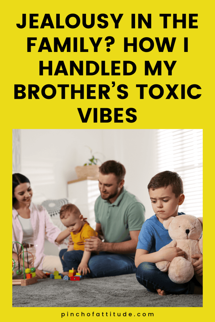 Pinterest - Pin with title "Jealousy in the Family? How I Handled My Brother’s Toxic Vibes" showing a family sitting on the floor where a boy holding a teddy bear looks upset while the parents and another child play in the background.