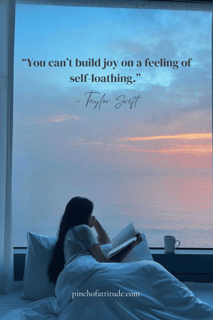 Pinterest - Pin with a quote by Taylor Swift that says "You can't build joy on a feeling of self-loathing." showing a woman in her bed clutching a book while looking at the sea through her window.