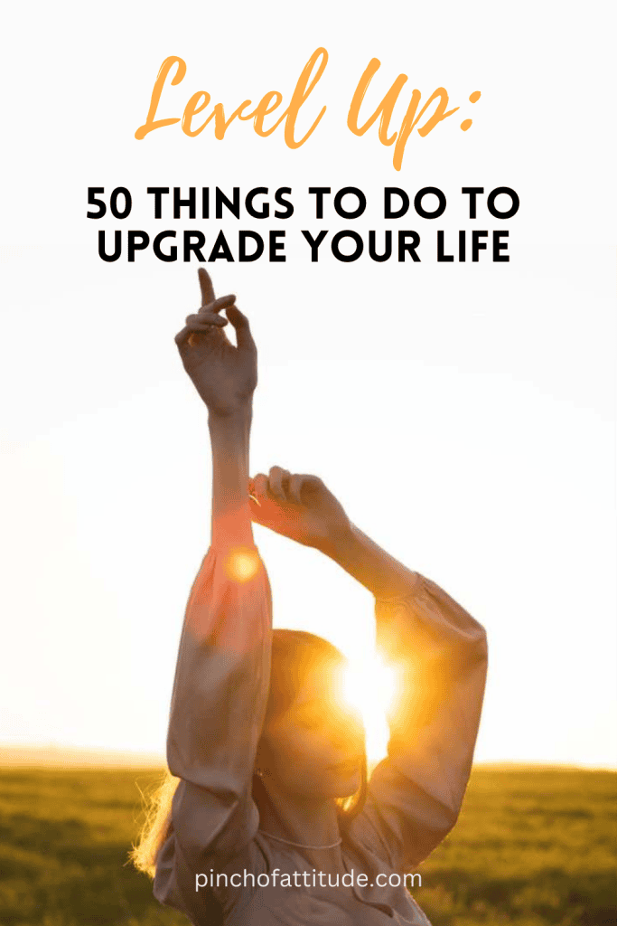 Pinterest - Pin with title "Level Up: 50 Things to Do to Upgrade Your Life" showing a woman standing outdoors, backlit by the sun, with her arms raised.