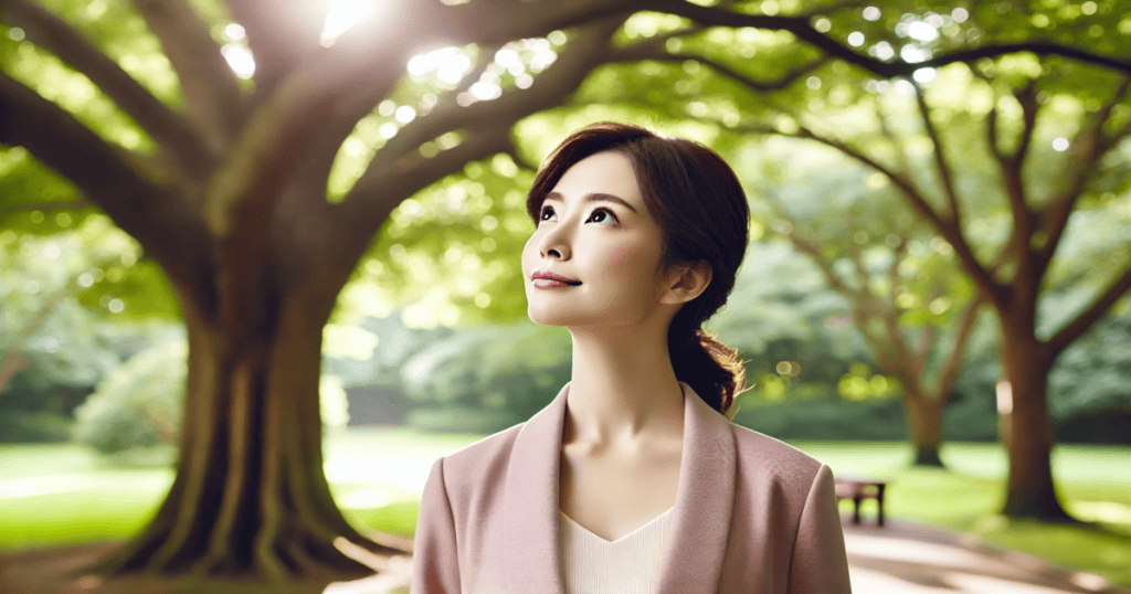 A woman standing under the shade of a large tree in a peaceful park, looking upward with a calm expression.