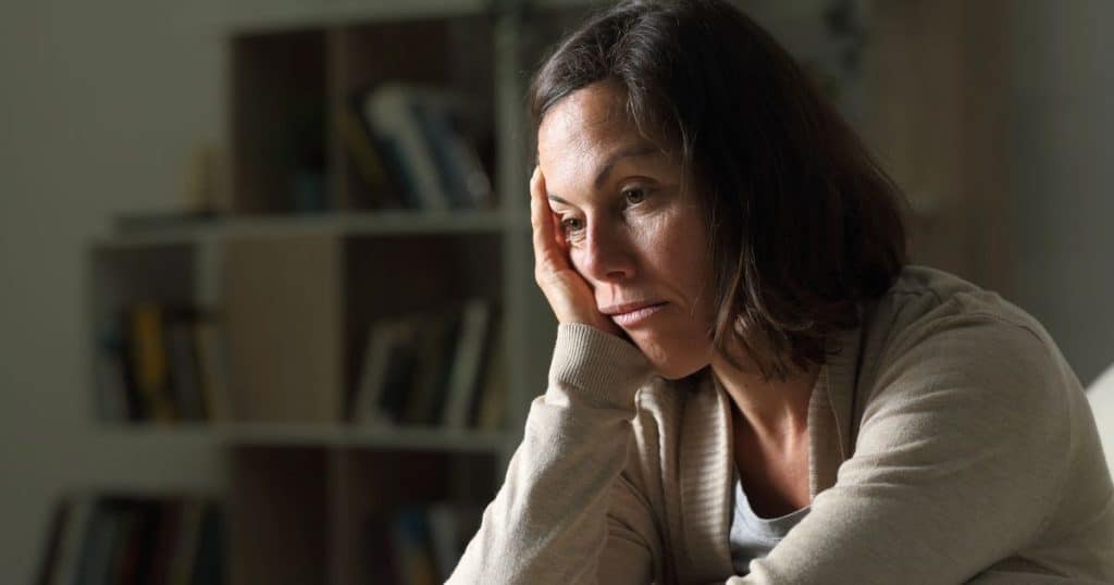 woman is looking bore sitting alone in her home.