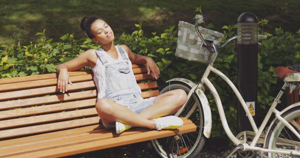 Woman enjoying sun on bench in park.