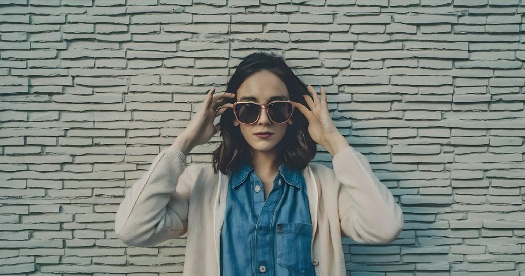 a woman wearing sunglasses and beige cardigan looking cool and unbother by her toxic family.