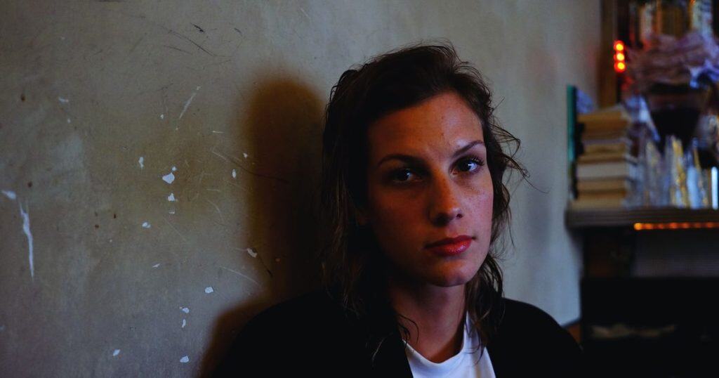 Close-up portrait of young woman at home with no emotion on her facing showing how gray rock method works.