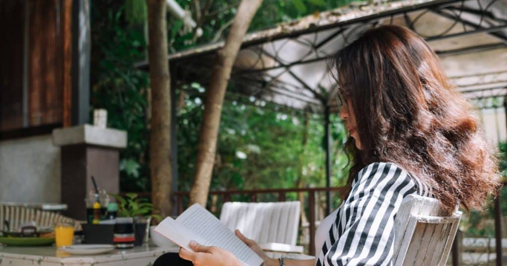 a woman wearing a zebra pattern blouse, sitting in the cafe reading a book smiling and enjoying her alone time from her toxic partner.