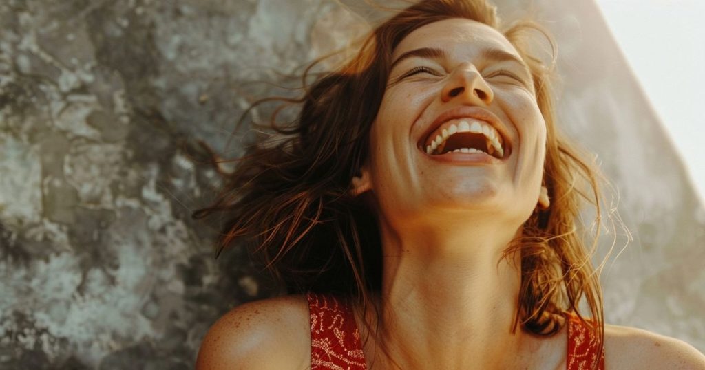 Portrait of woman showing strong emotions for mental health awareness laughing while looking up at the sun wearing a red dress with short brown hair.