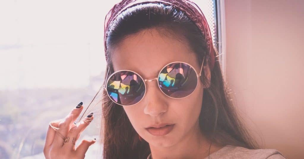 Close-up portrait of young woman wearing sunglasses while playing with her hair feeling confdient when dealing with her toxic siblings.