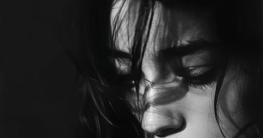 a close up of black and white image of a woman looking sad as she's looking down with no hope.
