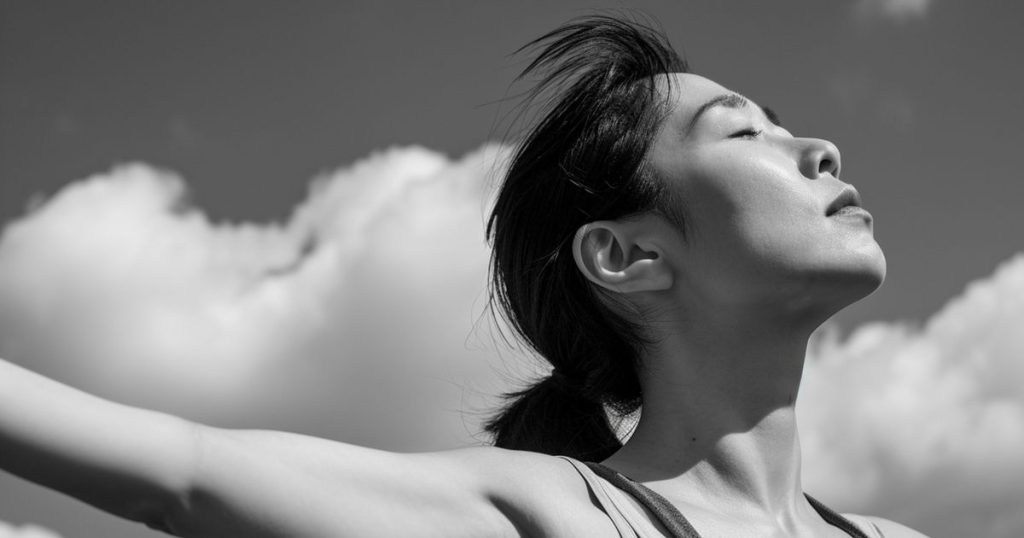 a black and white image of a asian woman with her short hair closing her eyes with her chin lift up feeling proud while soaking the sunlight.
