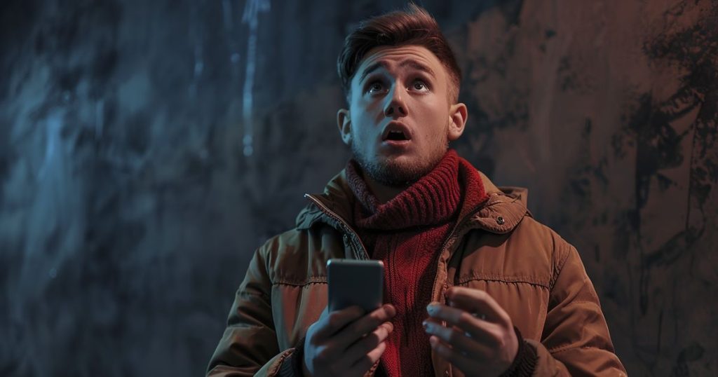 A Portrait Handsome Young Guy Holding a Mobile with his mouth opens and looking up in surprise.