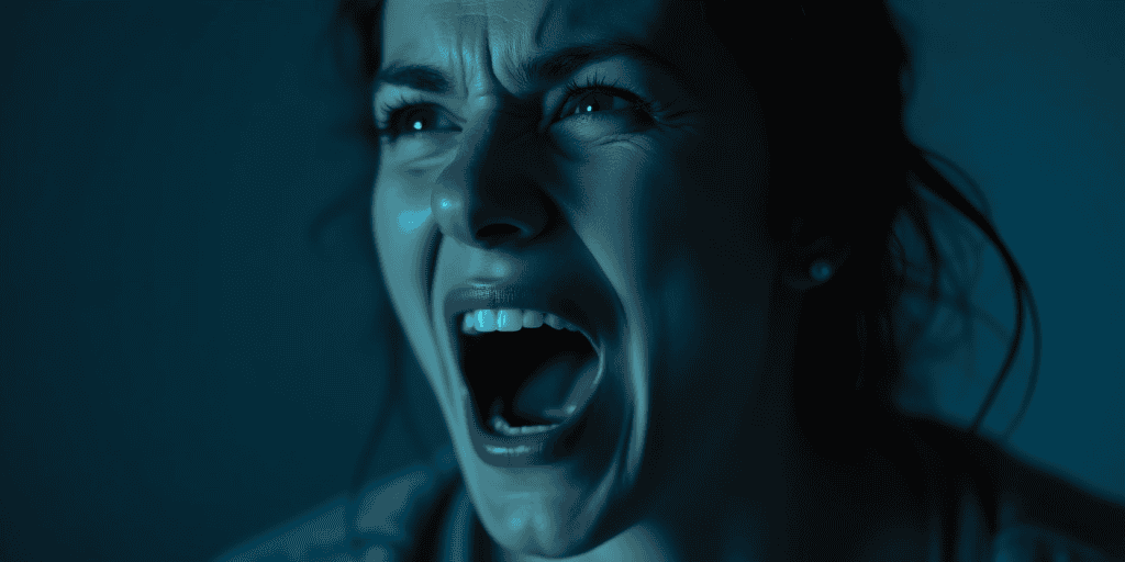 a closed up picture of a woman screaming in the dark looking very angry.