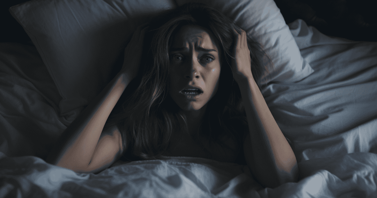 A distressed woman sits up in bed in the middle of the night, gripping her head in fear and confusion, illuminated by dim light in an otherwise dark room. This implies that when your mind won't rest, the chaos inside becomes the storm you can’t outrun.