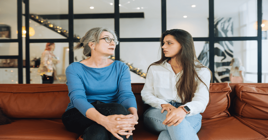 A daughter sits tensely beside her mother, quietly absorbing the blame just to avoid another emotional fallout.