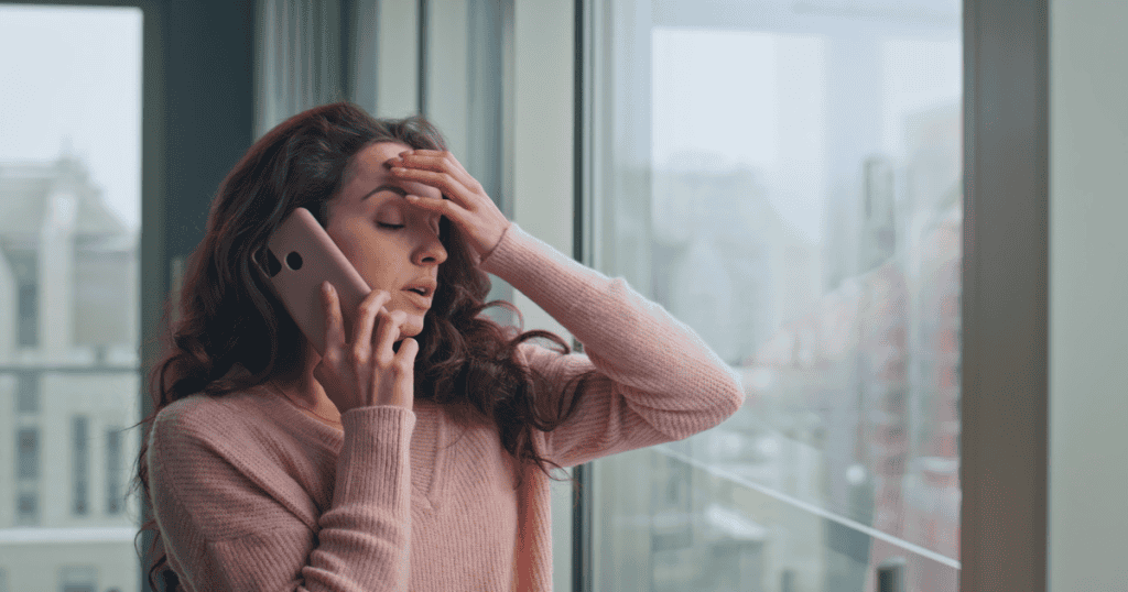 A woman on the phone pauses mid-conversation, trying to choose a calmer response instead of her usual emotional trigger.