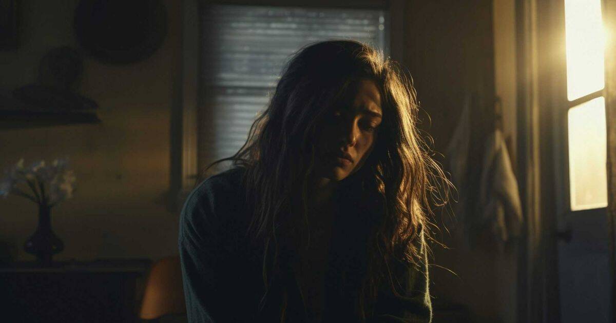 A young woman sits alone in a softly lit room, her face shadowed by sorrow and exhaustion. Sunlight from a window touches her hair, symbolizing a fragile hope as she silently carries the heavy burden of blame and self-blame.