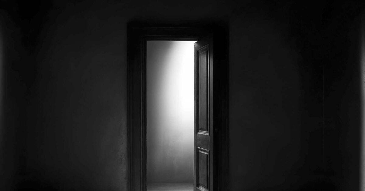 an image of black and white empty room with an open door.