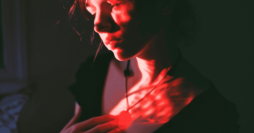 A person stands in dim light with a red glow cast across their chest and face, suggesting emotional distance and inner conflict, a visual echo of the harsh realities behind toxic family ties.