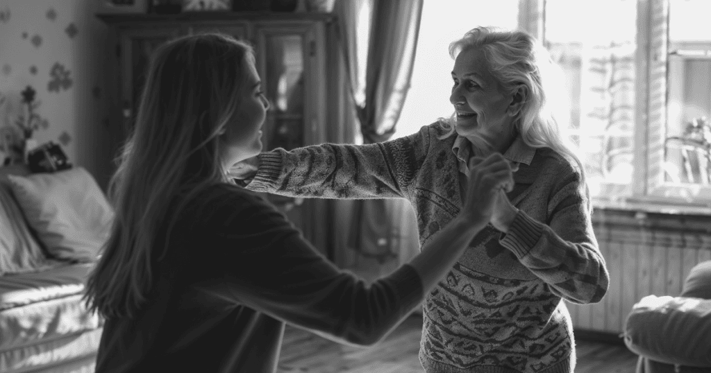 An older woman and a younger woman smile while dancing together in a cozy living room, reflecting how narcissists use soft reminders of good times to pull you back in.