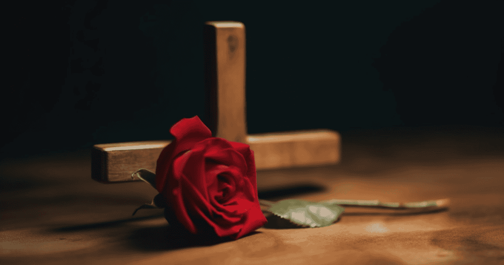 A single red rose rests before a wooden cross, symbolizing the painful but necessary hard truths you must hear when grieving narcissists who were never truly present.