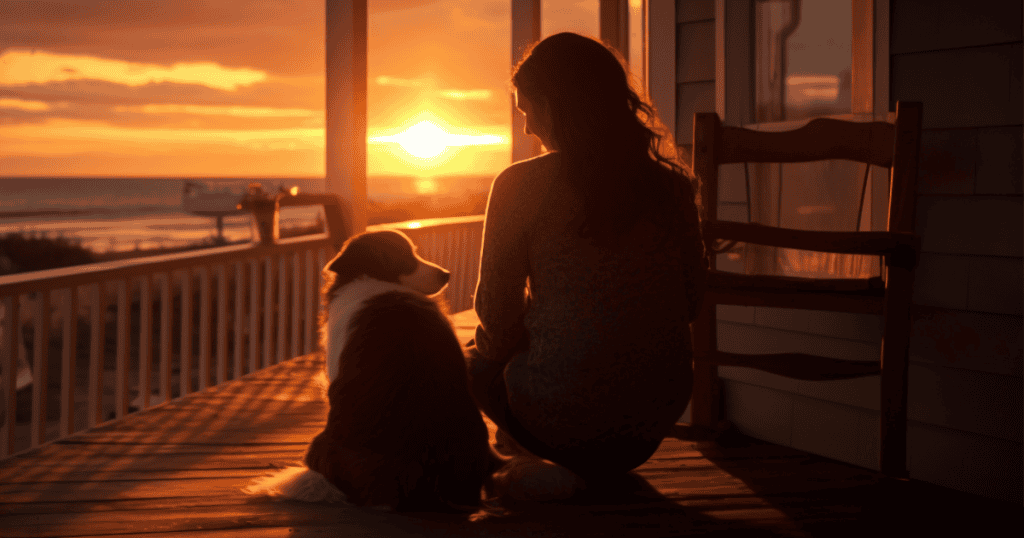 A woman sits beside her dog on a porch at sunset, symbolizing the grounding connections and quiet strength that keep grief from pulling you back in.