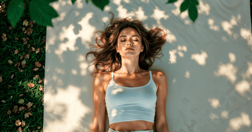 A woman lies calmly in dappled sunlight, embodying stillness and clarity as she chooses reset over chaos.