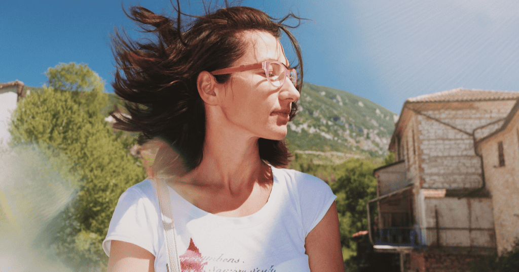 A woman standing confidently outdoors with the wind in her hair, symbolizing the unshakable independence that leaves narcissists powerless.