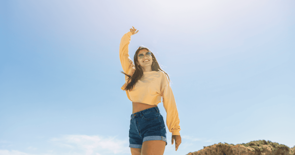 A confident woman smiling under the bright sky, embodying the freedom and strength that makes her untouchable to a narcissist.