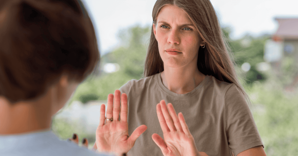 A woman raising her hands in a stop gesture, showing the need to set firm boundaries with her narcissistic family.