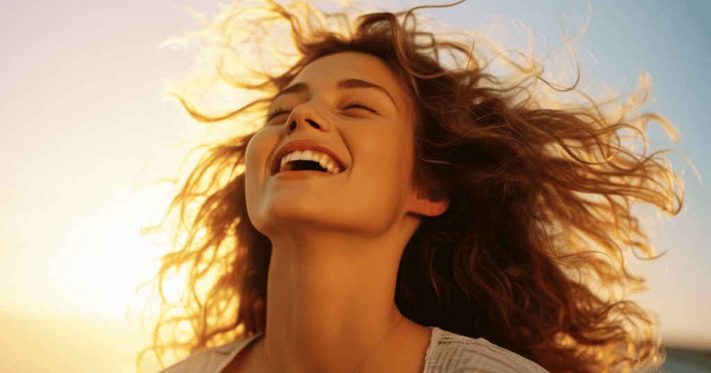 A woman laughs freely in the golden light of sunset, radiating liberation and peace.