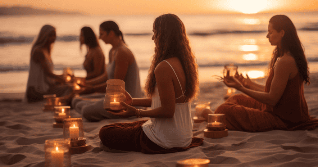 A group of women sit on the beach at sunset holding candles, symbolizing the clarity and courage to pursue one’s deepest desires without fear of failure.