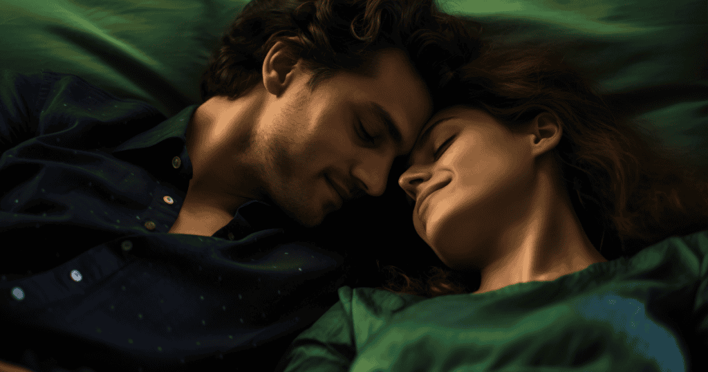 A man and woman lie close together with their foreheads touching, sharing a tender smile that conveys warmth while subtly reinforcing a dynamic of reward and control.