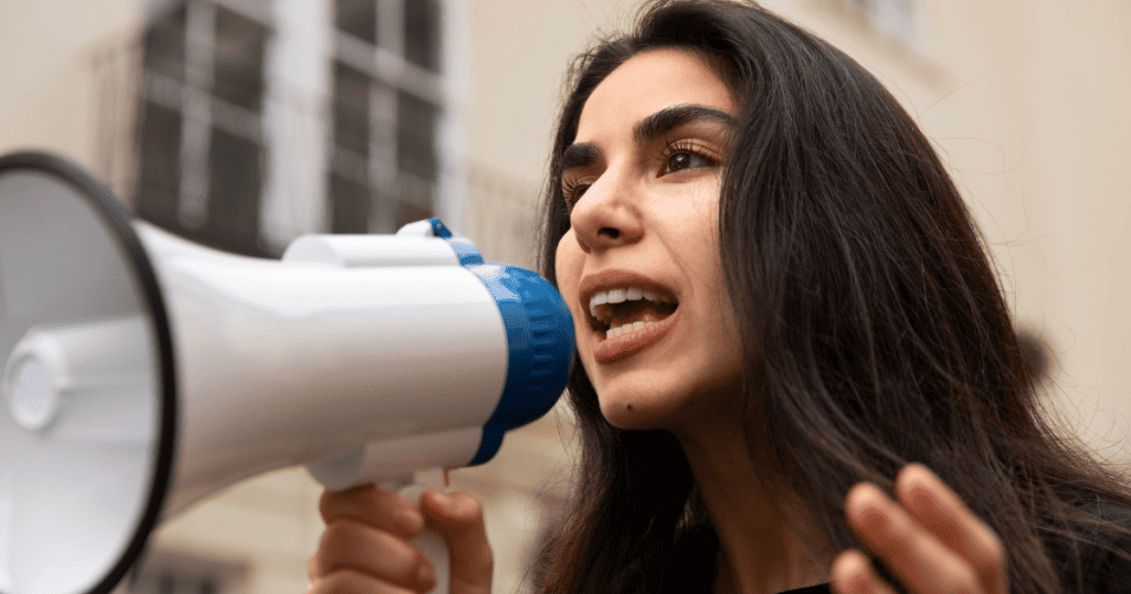 A woman speaks into a megaphone with determination, representing the need to call out narcissistic abuse clearly.