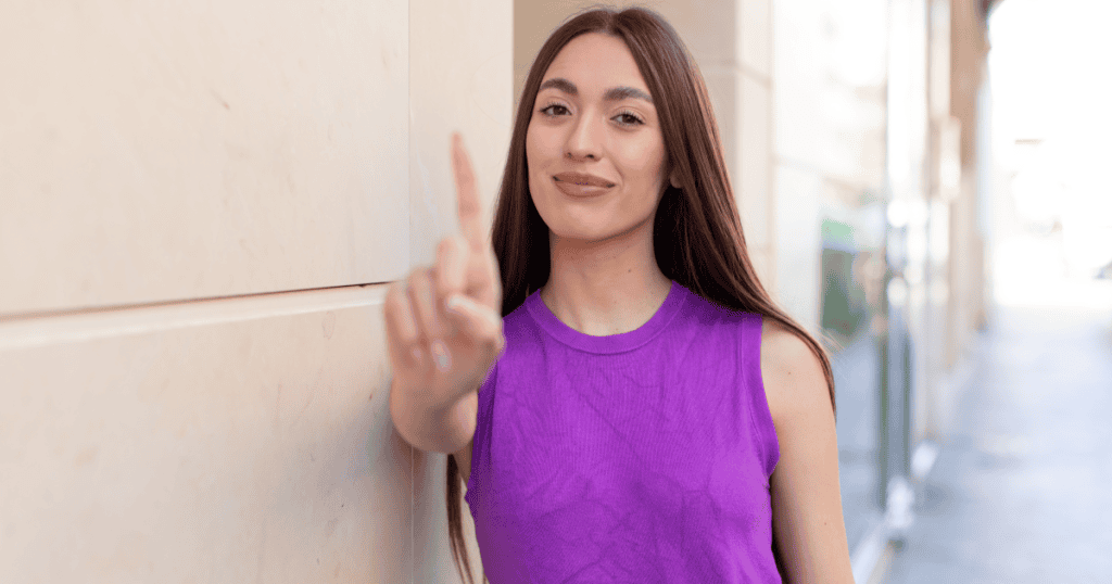 A confident woman raises her finger to signal no, cutting off the fixer role and refusing responsibility for the narcissist’s happiness.