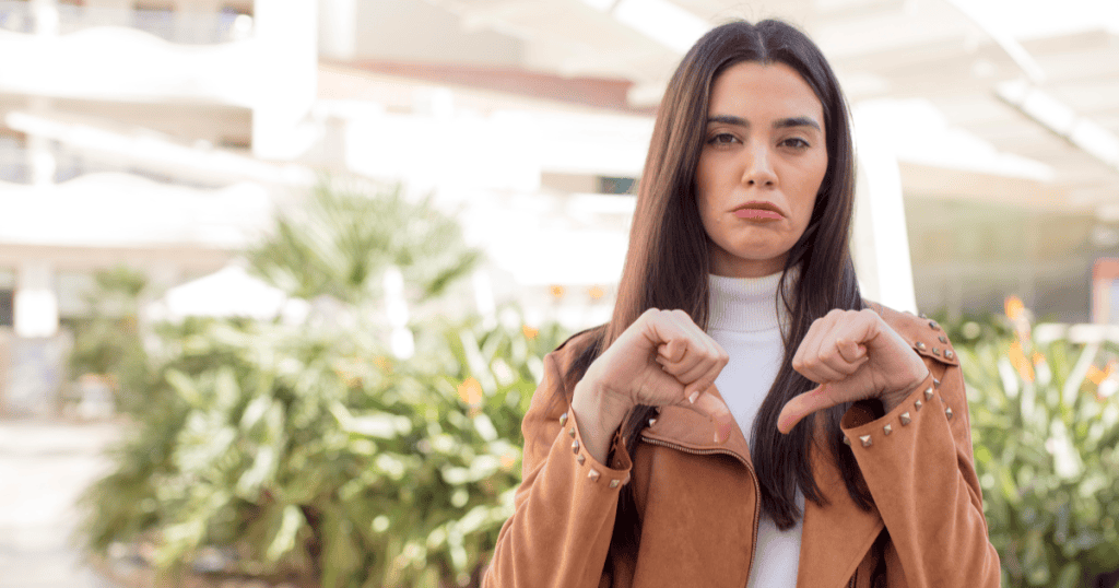 A woman gives two thumbs down with a serious expression, emphasizing that forgiving a narcissist doesn’t mean trusting them again.