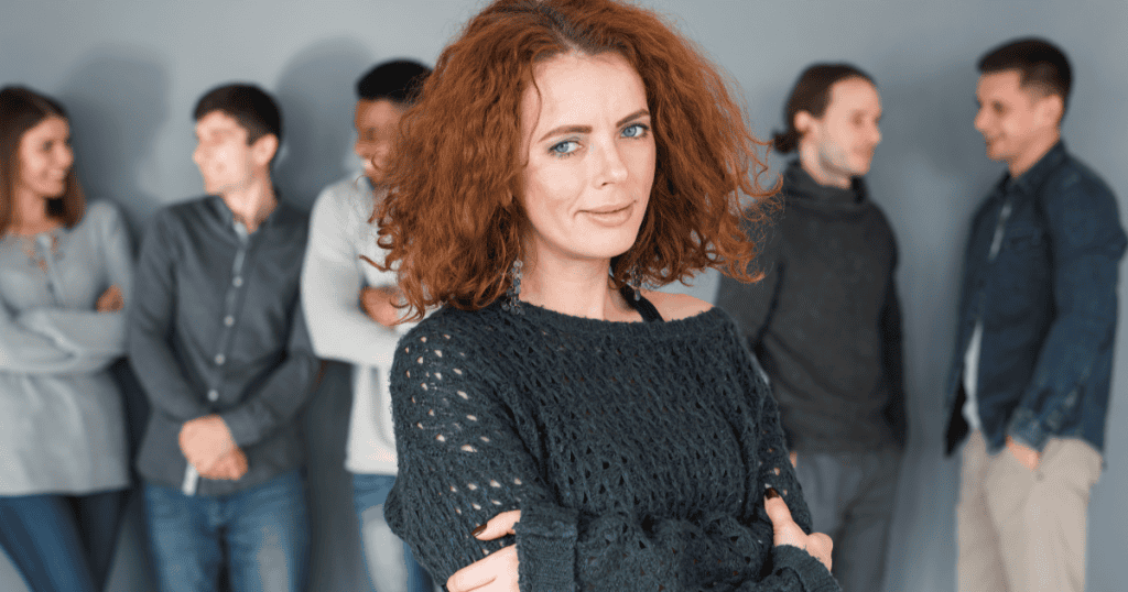 A woman stands confidently in front of a group whispering behind her, symbolizing forgiving narcissists who lied without letting them control her.