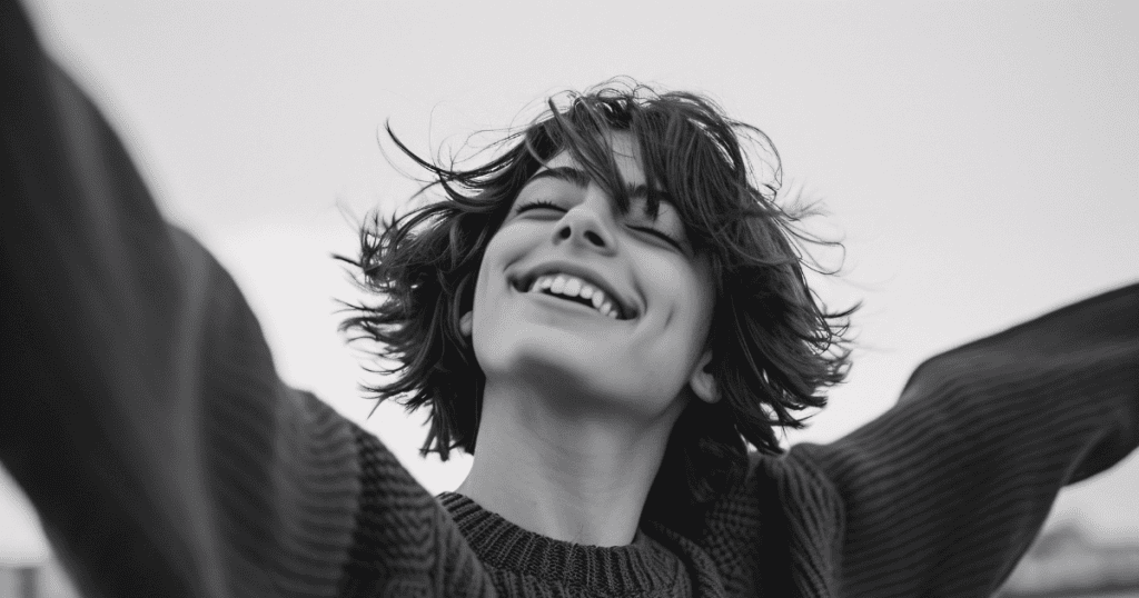 A joyful young woman smiles with arms outstretched in the wind, symbolizing how finding happiness after narcissists becomes a bold and strategic act of rebellion.