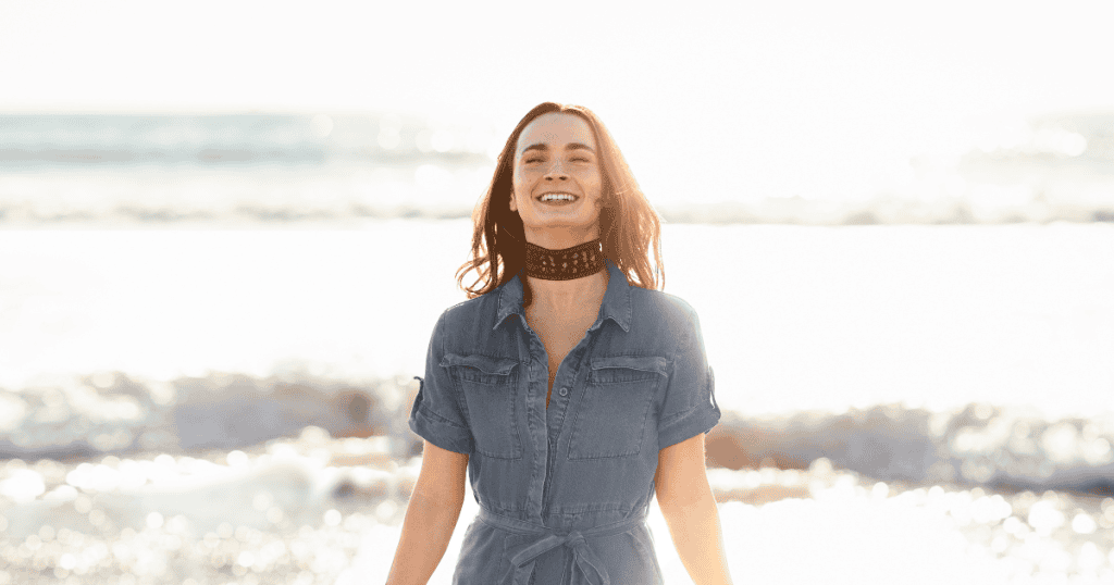 A smiling woman stands confidently by the ocean, symbolizing how survivors can use knowledge about narcissists to reclaim freedom and joy.
