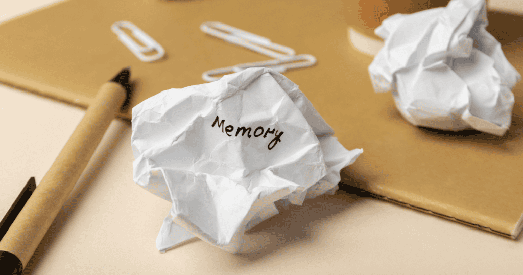 A crumpled piece of paper with the word “Memory” written on it, placed on a desk with a pen, paperclips, and other crumpled papers. This visual represents how narcissists distort and discard memories, rewriting reality to suit their narrative.