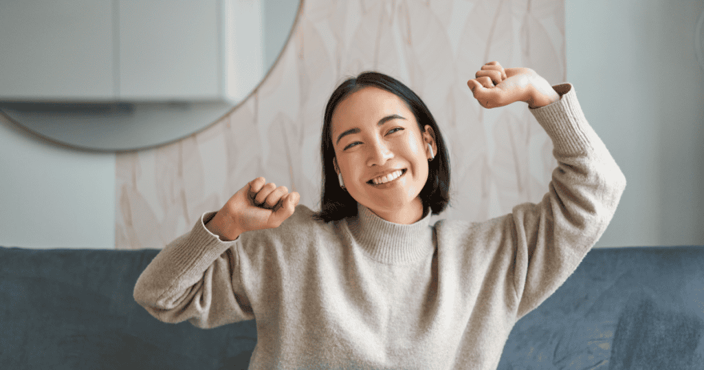 An optimistic woman smiles and raises her arms in joy after a life with narcissist.
