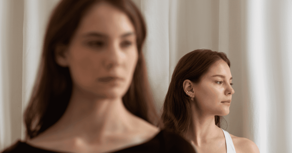 Two women stand indoors with one in focus looking away and the other blurred in the foreground, reflecting the message to stop expecting validation from them.