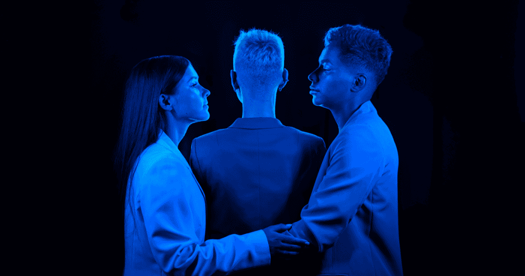 Three people in blue lighting stand together, symbolizing the Dark Triad traits of narcissism, psychopathy, and Machiavellianism.
