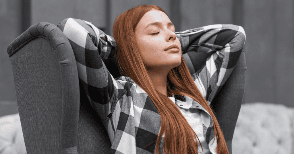 A young woman relaxes in a chair with her hands behind her head and eyes closed, symbolizing the power of naming the trap and reclaiming peace.