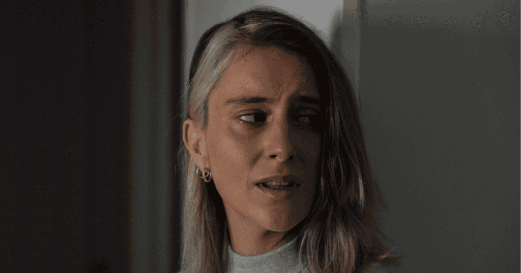 A distressed woman with tears in her eyes looks away in a dimly lit room, capturing the pain behind the ugly tactics narcissists use to tear you down.