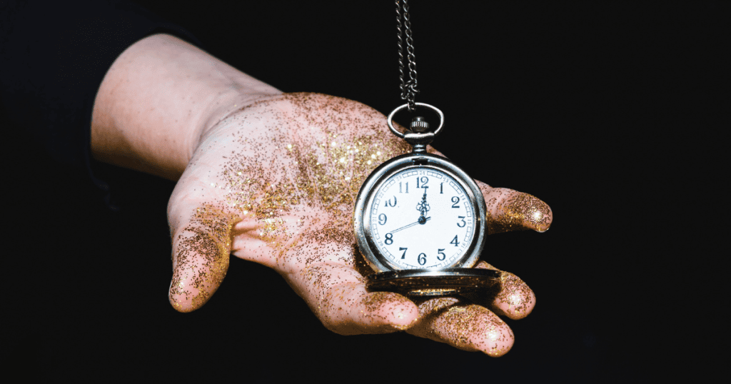 A hand covered in gold glitter holds a pocket watch on a chain, symbolizing how time spent on narcissists feels like precious time stolen from you.