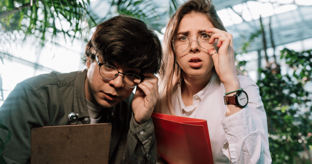 Two people in glasses look closely and confused while holding folders, symbolizing the need to describe the impact of narcissists’ actions, not just their behavior.