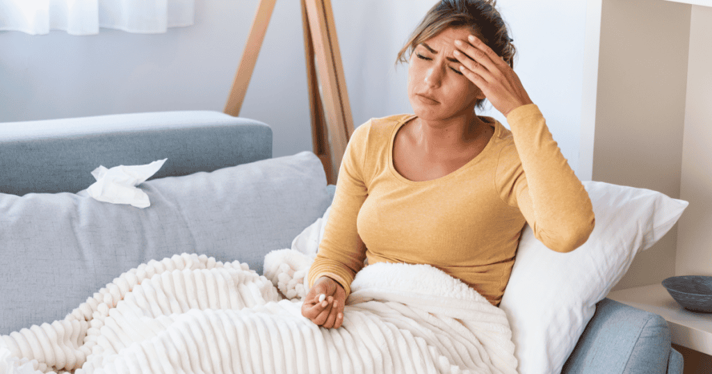 A narcissistic woman lies on the couch with her hand on her forehead, looking unwell.