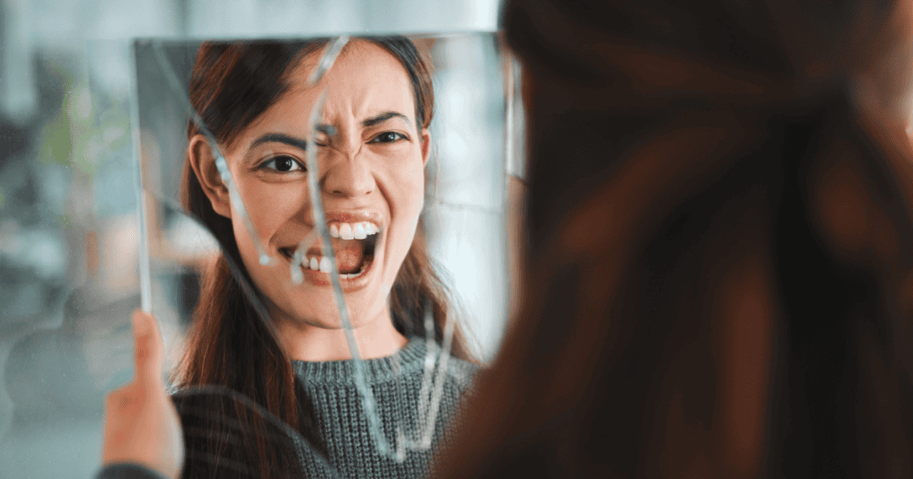 Woman looking into a cracked mirror, her reflection showing anger and distortion, symbolizing how setting firm boundaries disrupts a narcissist’s control and shatters their illusion of dominance.