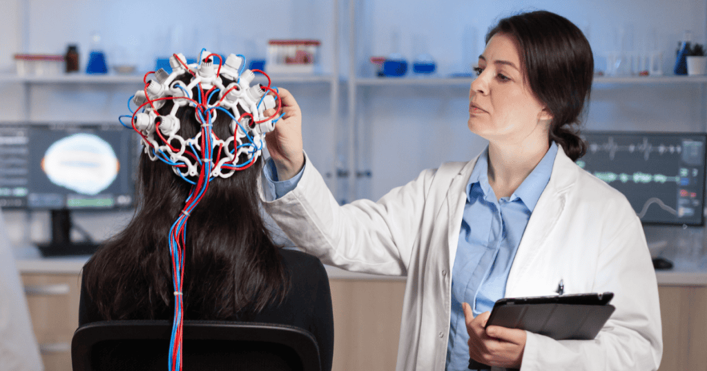 A female scientist adjusts brain monitoring equipment on a woman’s head in a lab, illustrating daily habits that rewire and protect your brain.